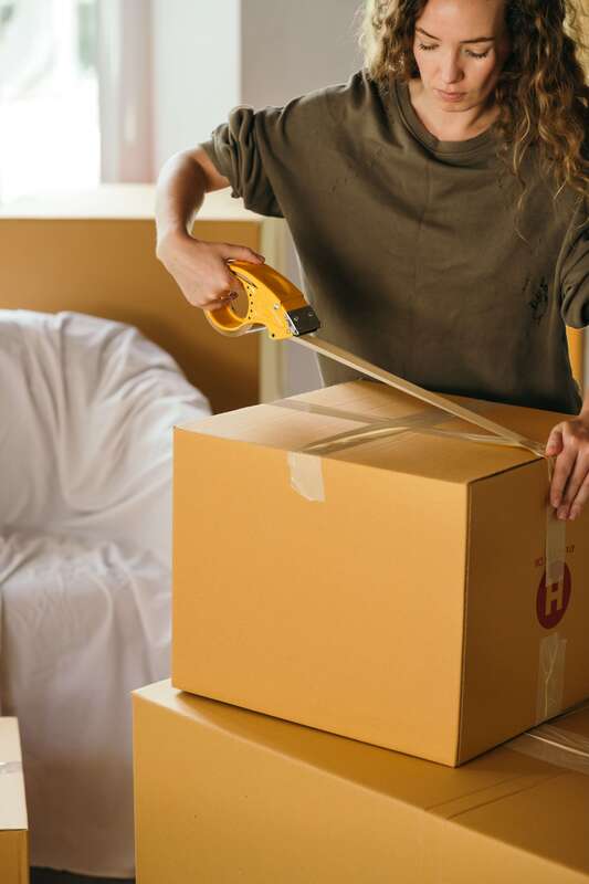 Woman taping cardboard boxes for moving